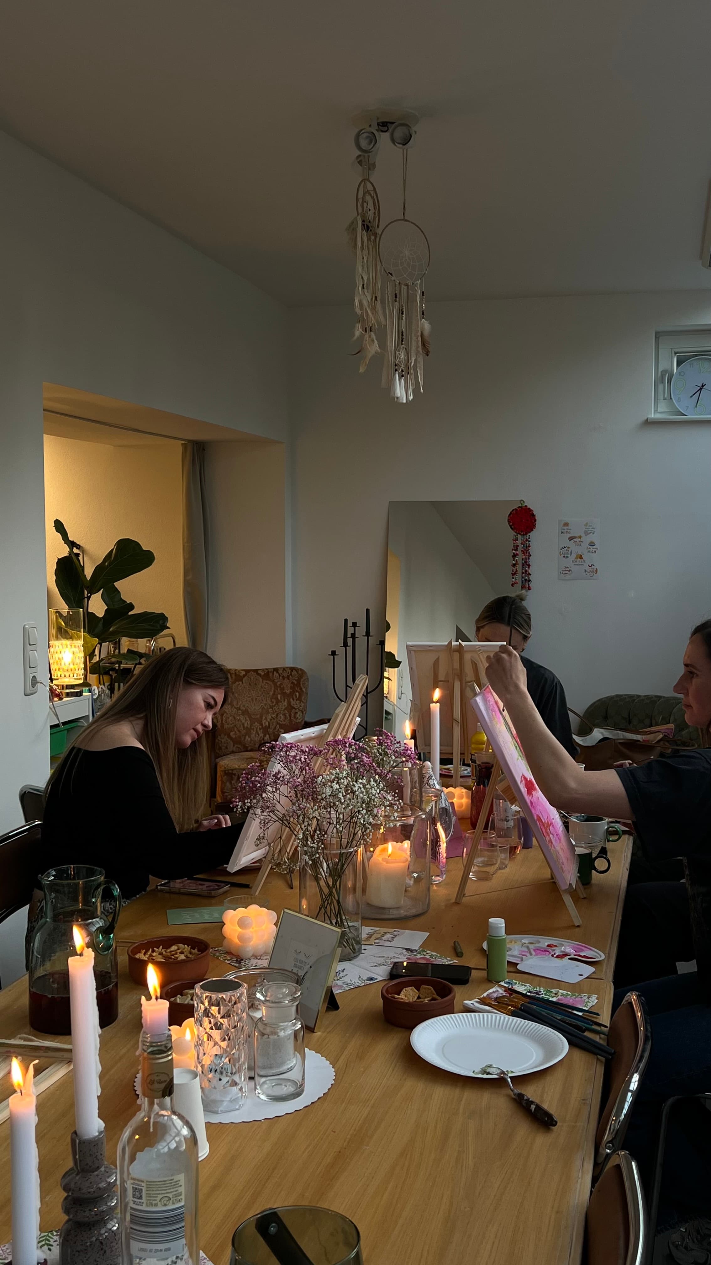 Gruppe von Frauen am langen Tisch im HeimART Studio beim gemeinsamen Malen, brennende Kerzen und warme Abendstimmung